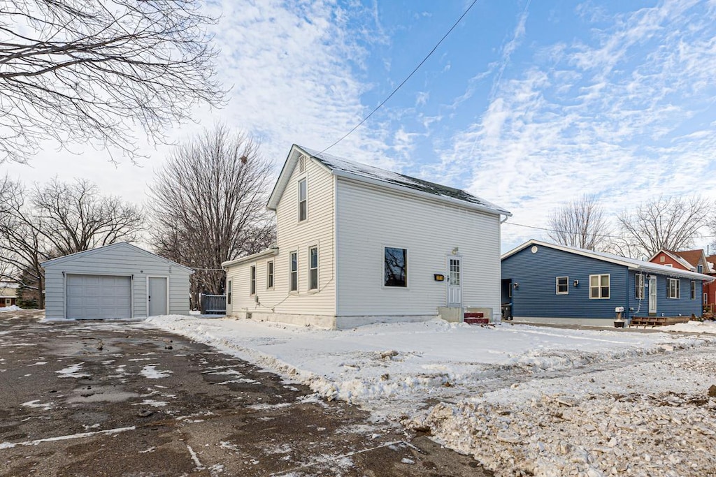 view of snow covered exterior with a garage, central air condition unit, and an outbuilding