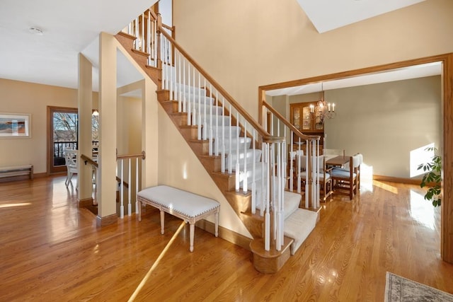 stairway featuring hardwood / wood-style flooring, an inviting chandelier, and a high ceiling