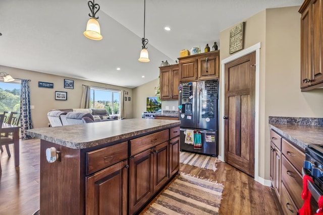 kitchen featuring refrigerator with ice dispenser, vaulted ceiling, dark countertops, dark wood-style floors, and recessed lighting