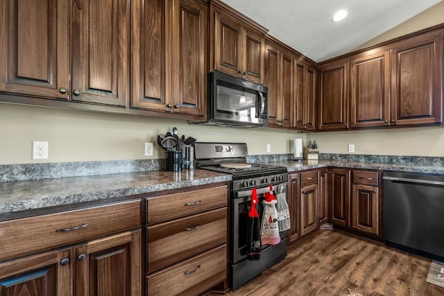 kitchen with stainless steel appliances, dark countertops, dark wood-style floors, lofted ceiling, and recessed lighting