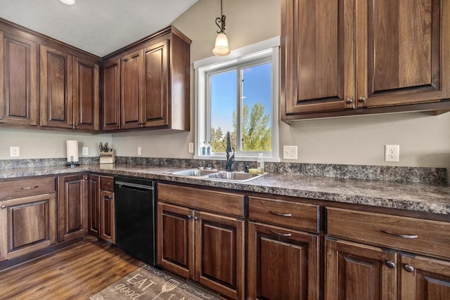 kitchen featuring black dishwasher, dark countertops, a sink, dark wood-style floors, and pendant lighting