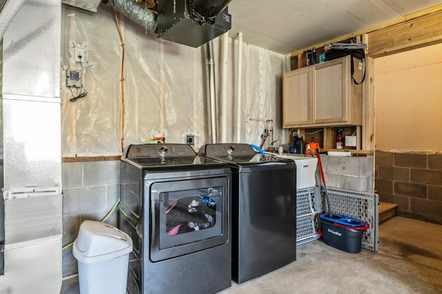laundry area with washing machine and clothes dryer, cabinet space, and concrete block wall