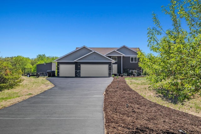 view of front of house featuring asphalt driveway, an attached garage, and stone siding
