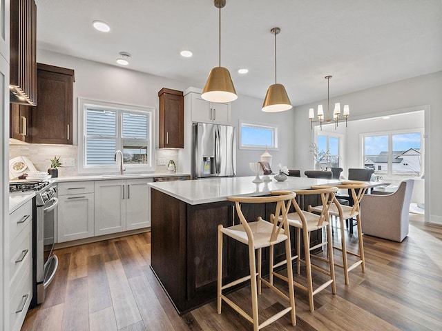 kitchen featuring decorative light fixtures, stainless steel appliances, a kitchen island, and white cabinetry