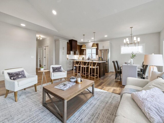 living room with vaulted ceiling, light hardwood / wood-style flooring, and a chandelier