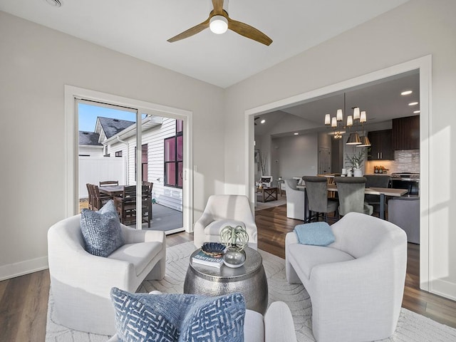 living room with ceiling fan with notable chandelier and dark hardwood / wood-style floors