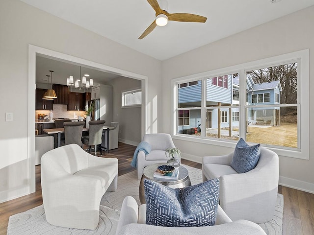 living room with ceiling fan with notable chandelier and hardwood / wood-style flooring