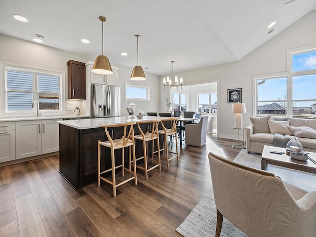 kitchen with pendant lighting, dark hardwood / wood-style floors, a kitchen island, and stainless steel fridge with ice dispenser