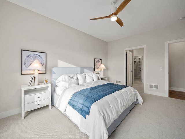 carpeted bedroom with a walk in closet and ceiling fan