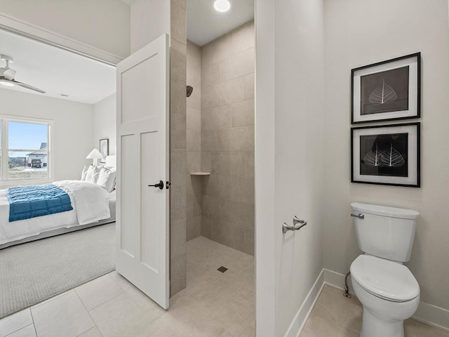 bathroom featuring tile patterned flooring, a tile shower, toilet, and ceiling fan