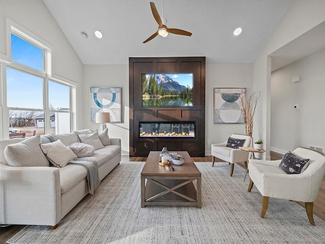 living room featuring ceiling fan, a fireplace, vaulted ceiling, and hardwood / wood-style flooring