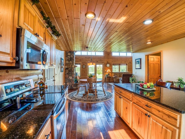 kitchen with appliances with stainless steel finishes, wood ceiling, hardwood / wood-style flooring, dark stone countertops, and lofted ceiling