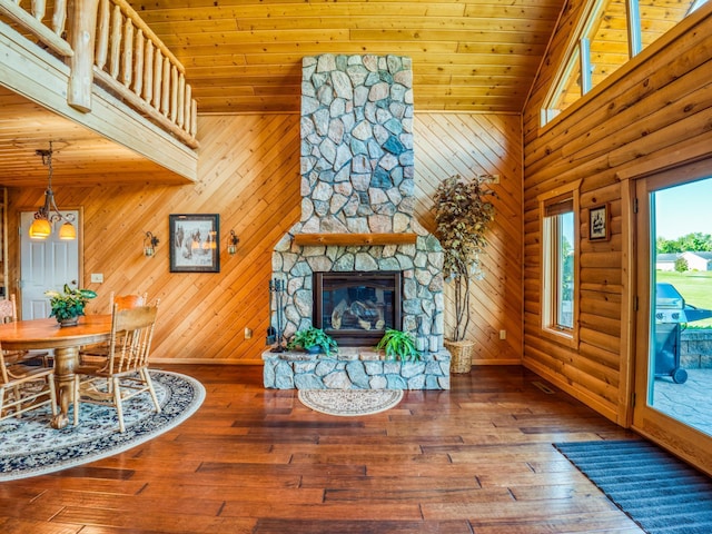 living room featuring hardwood / wood-style floors, wood walls, high vaulted ceiling, a fireplace, and wood ceiling