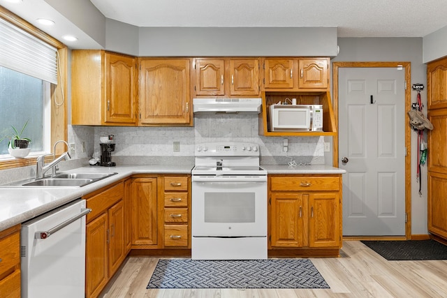 kitchen with decorative backsplash, white appliances, light hardwood / wood-style flooring, and sink