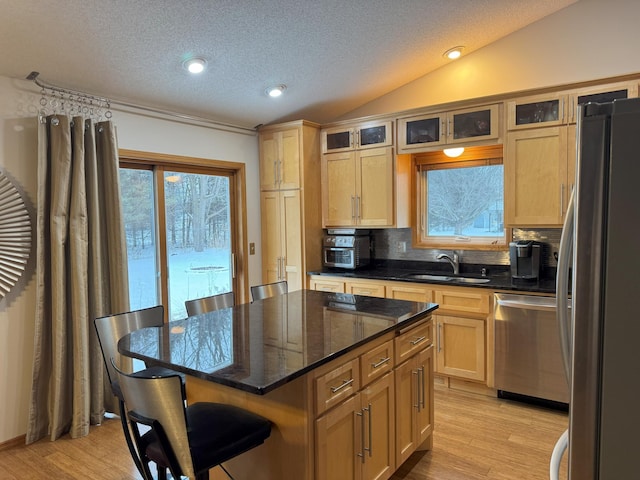 kitchen featuring a breakfast bar, stainless steel appliances, sink, a kitchen island, and lofted ceiling