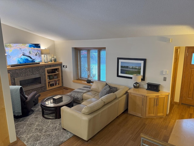 living room featuring vaulted ceiling, a textured ceiling, and light hardwood / wood-style flooring