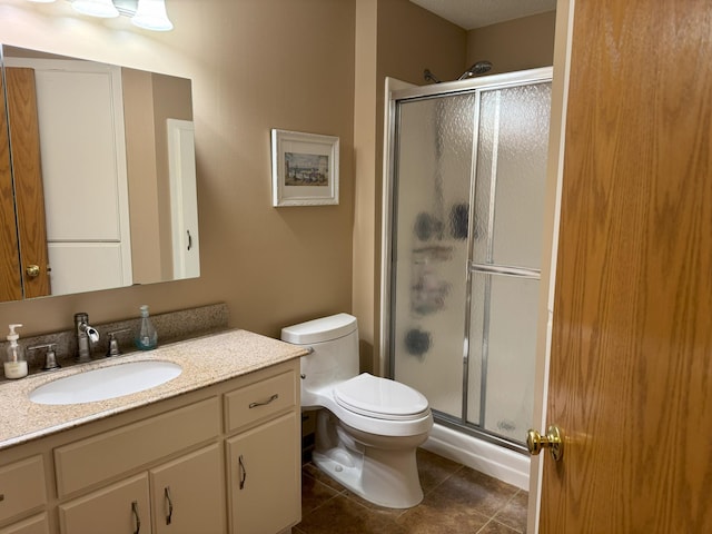 bathroom with tile patterned floors, vanity, toilet, and a shower with door