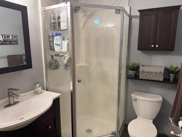 bathroom featuring a shower with door, vanity, and toilet