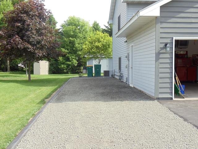 view of side of property featuring a shed, a yard, and central AC