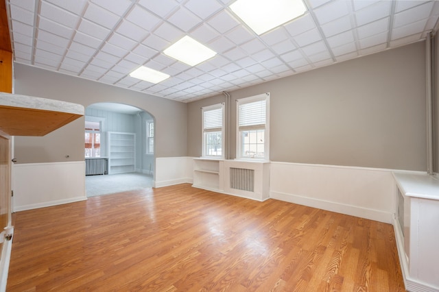 unfurnished living room featuring a paneled ceiling, plenty of natural light, and light hardwood / wood-style floors