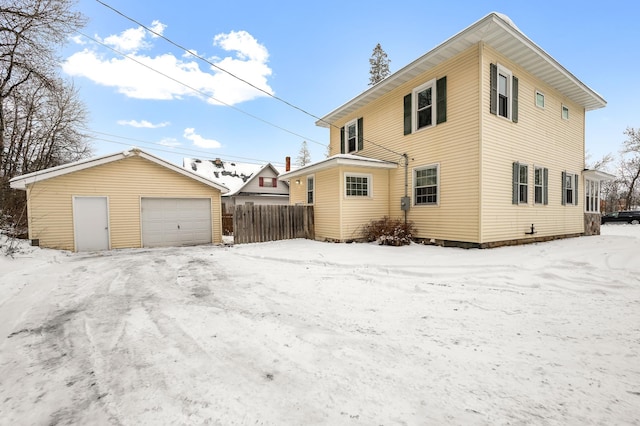 snow covered property featuring a garage and an outdoor structure