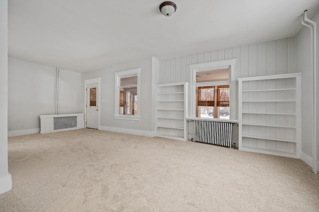 unfurnished living room with light colored carpet and radiator