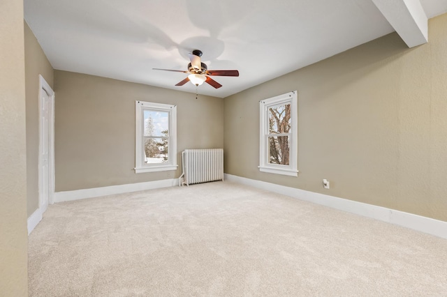 carpeted empty room with ceiling fan and radiator