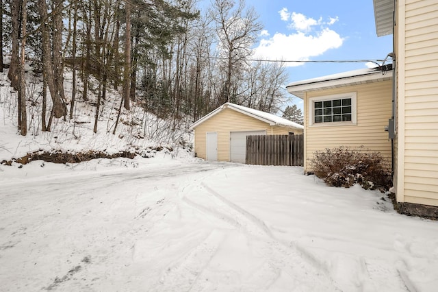 yard layered in snow featuring an outbuilding and a garage