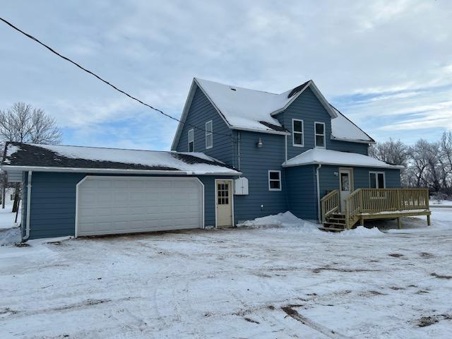 snow covered property with a garage