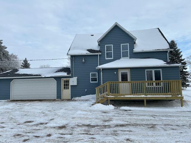 snow covered back of property with a garage