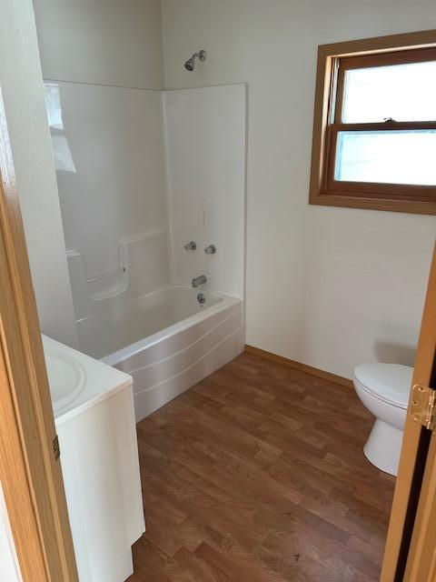 full bathroom with hardwood / wood-style floors, vanity, toilet, and tub / shower combination