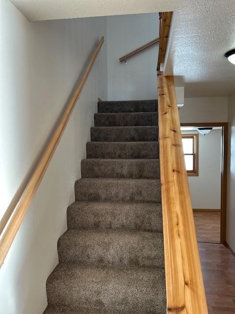 stairs featuring a textured ceiling and hardwood / wood-style flooring