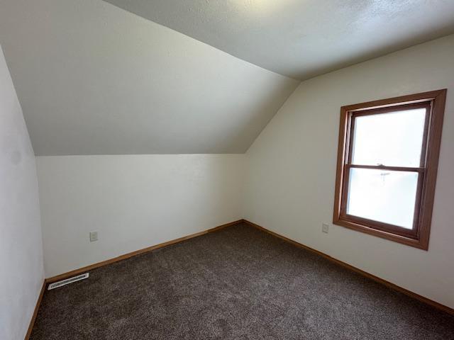 bonus room featuring lofted ceiling, carpet, baseboards, and visible vents