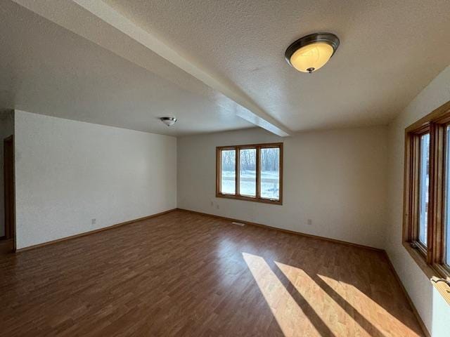 empty room featuring dark wood-style floors, baseboards, and a textured ceiling