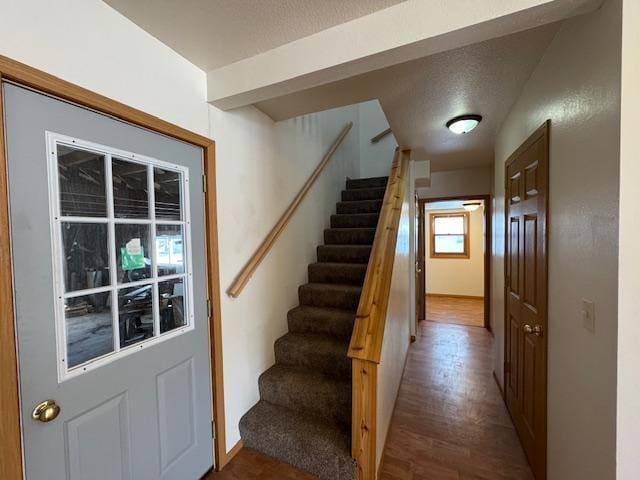 stairs with a textured ceiling and wood finished floors