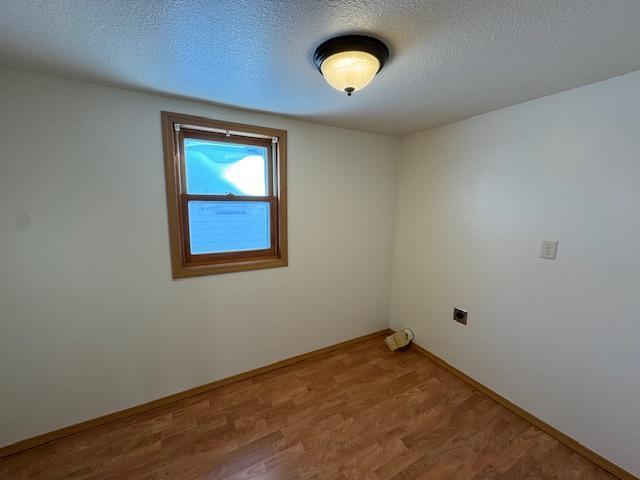 empty room featuring a textured ceiling, baseboards, and wood finished floors