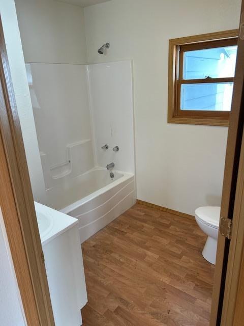 bathroom with shower / bath combination, vanity, toilet, and wood finished floors