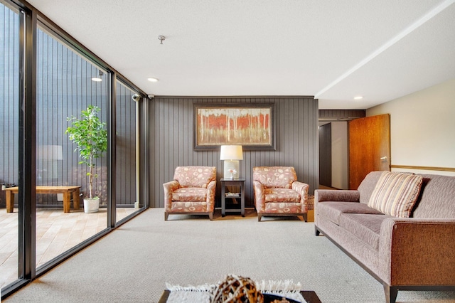 carpeted living room with wooden walls and a wall of windows