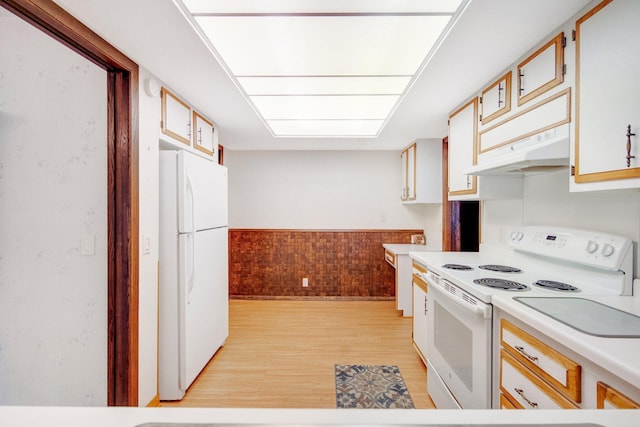 kitchen featuring white cabinets, wood walls, light wood-type flooring, and white appliances