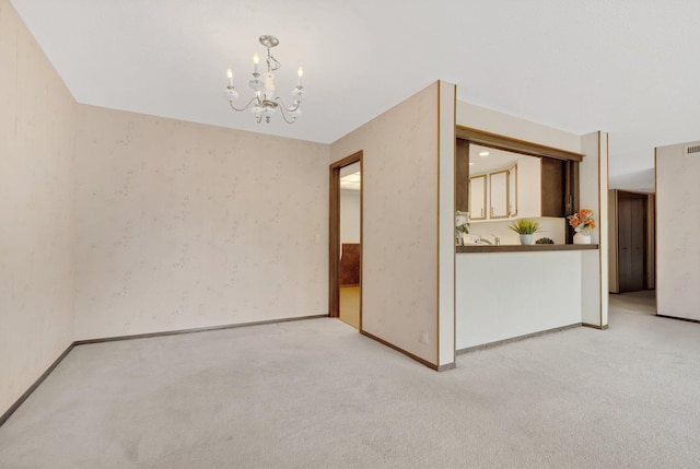 carpeted spare room with an inviting chandelier