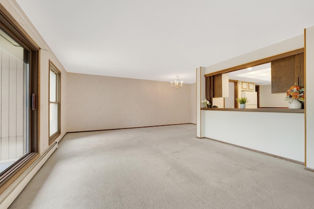 unfurnished room featuring carpet, a baseboard heating unit, and a notable chandelier