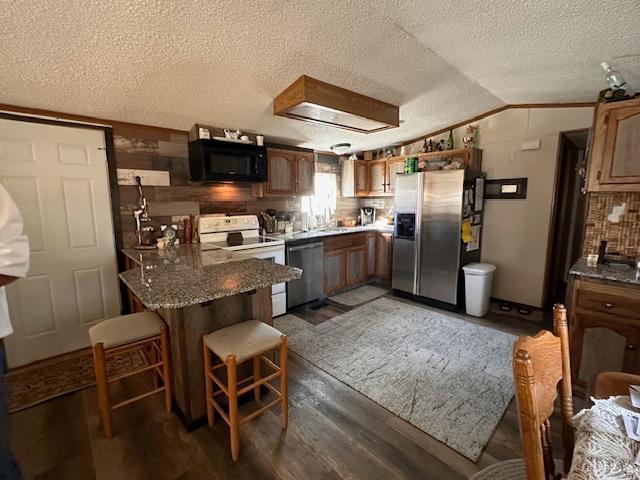 kitchen with lofted ceiling, dark wood-type flooring, sink, a textured ceiling, and appliances with stainless steel finishes