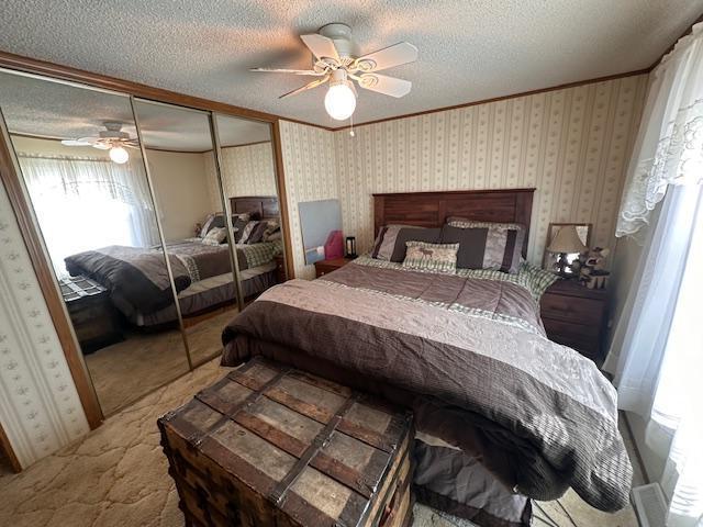 bedroom featuring carpet, ceiling fan, ornamental molding, a textured ceiling, and a closet