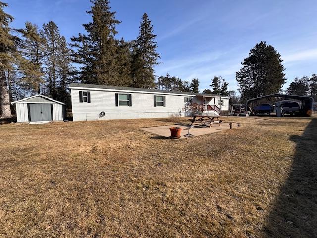 view of front facade with a front yard, a patio, and a storage shed