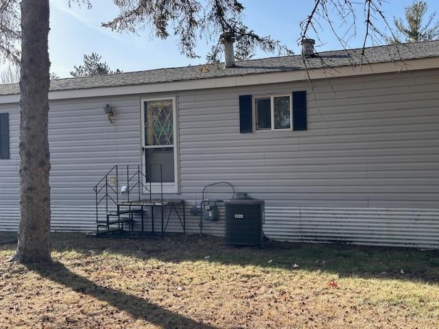 view of property exterior featuring central AC unit and a lawn