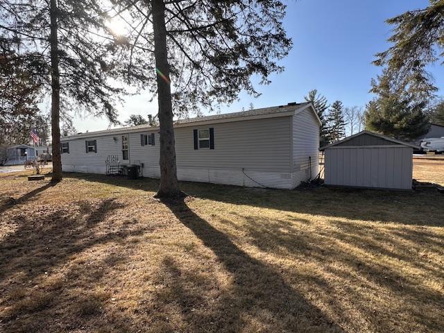 back of property featuring a shed and a lawn