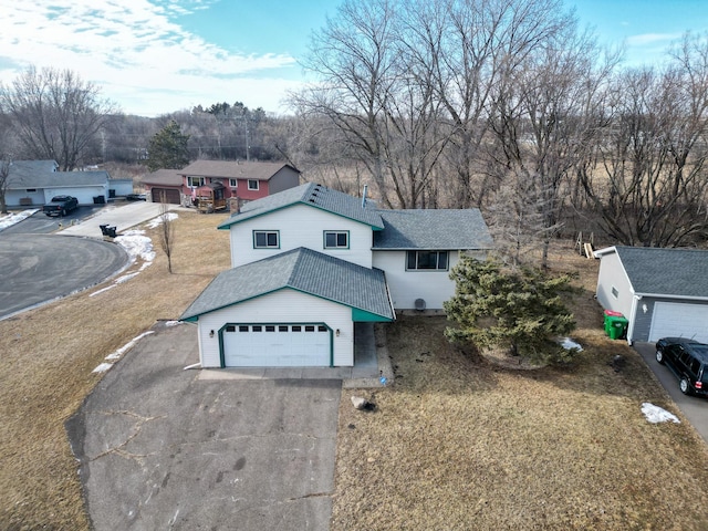 view of front of house with a garage, roof with shingles, and driveway