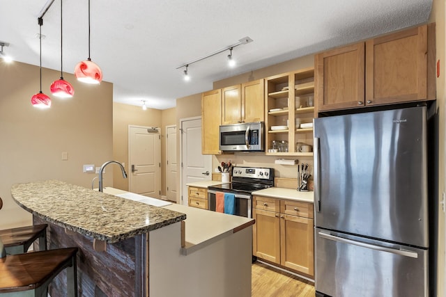 kitchen with sink, pendant lighting, a kitchen island with sink, a breakfast bar, and appliances with stainless steel finishes