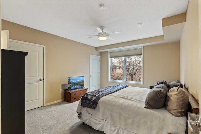 bedroom with ceiling fan, light colored carpet, and a textured ceiling