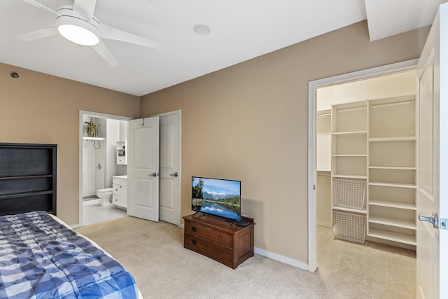 bedroom featuring ceiling fan, ensuite bath, light carpet, and a closet